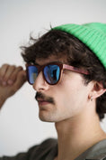 Load image into Gallery viewer, A man wearing a green hat and sunglasses made of Purpleheart wood.