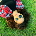 Load image into Gallery viewer, A woman wearing Yellowheart wood sunglasses, lying on the grass, enjoying the sun's warmth and relaxation.