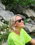 Load image into Gallery viewer, A woman in a neon green shirt and Wenge wood sunglasses sitting on a rock.