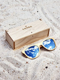 Load image into Gallery viewer, Maple wooden sunglasses with silver polarized lenses and a box on sandy beach.