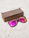 Load image into Gallery viewer, Wenge wooden sunglasses with red polarized lenses and a box on sandy beach.
