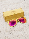 Load image into Gallery viewer, Yellowheart wooden sunglasses with red polarized lenses and a box on sandy beach.