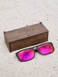 Load image into Gallery viewer, Wenge wooden sunglasses with red polarized lenses and a box on sandy beach.
