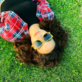 Load image into Gallery viewer, A woman wearing Yellowheart wood sunglasses, lying on the grass, enjoying the sun's warmth and relaxation.
