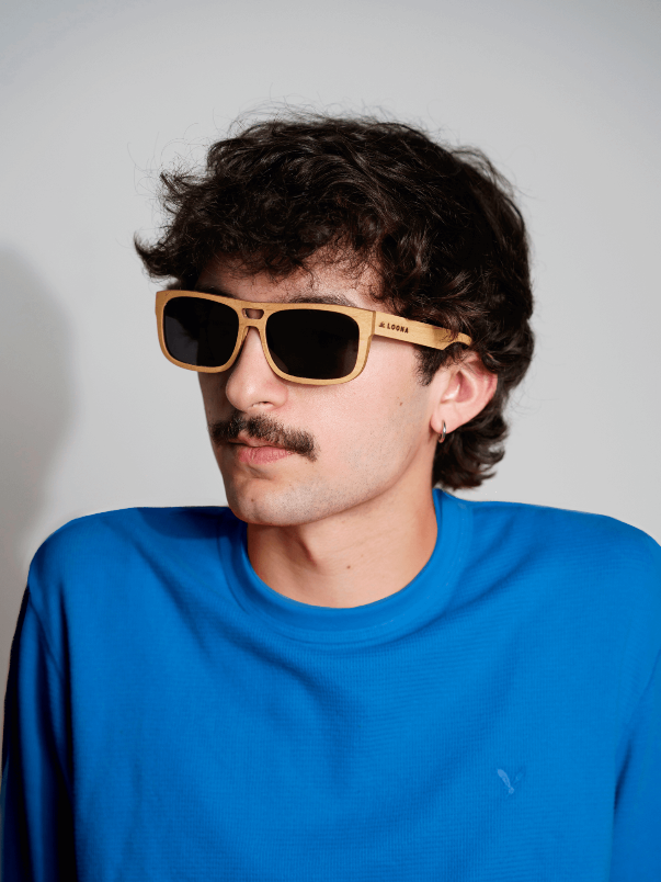 A man in a blue shirt wearing maple wood sunglasses.
