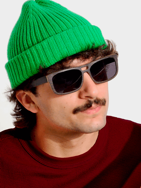 A man wearing a green hat and sunglasses made of Wenge wood, looking stylish and trendy.