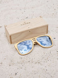 Load image into Gallery viewer, Maple wooden sunglasses with silver polarized lenses and a box on sandy beach.
